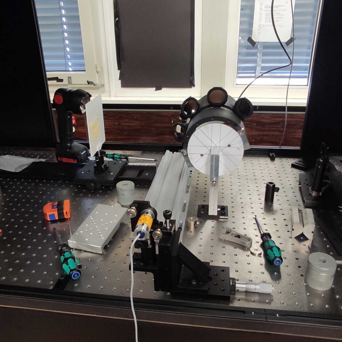 This optical setup was used to align eight spherical mirrors for the KTAG detector. A small laser (bottom, center) shines light towards the mirror support, where four mirrors can be seen. The light is reflected onto a target on the left of the picture.