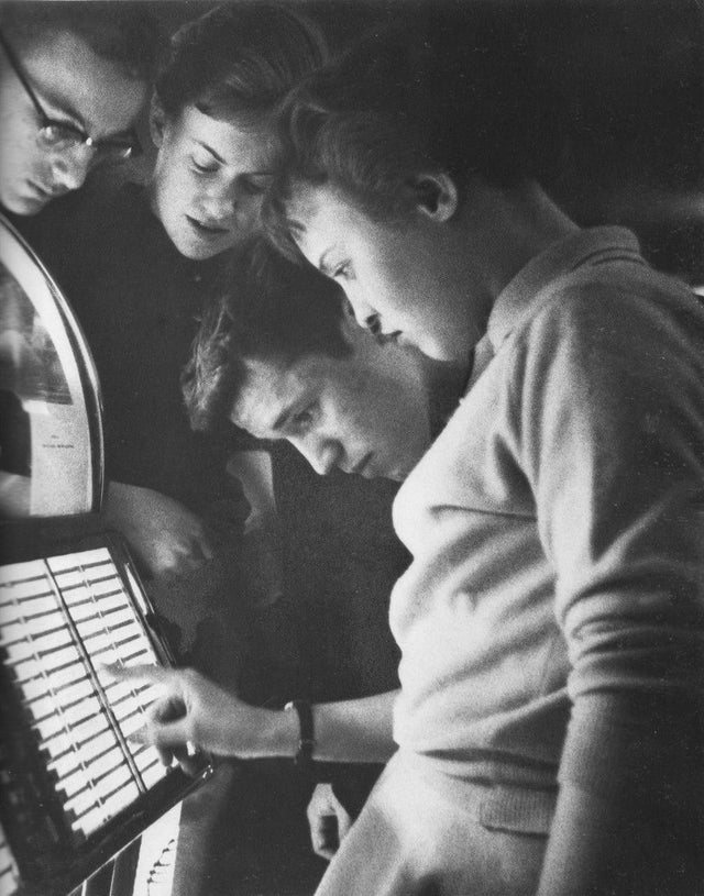 - Un grupo de adolescentes escogiendo una canción en la máquina de discos, 1950.