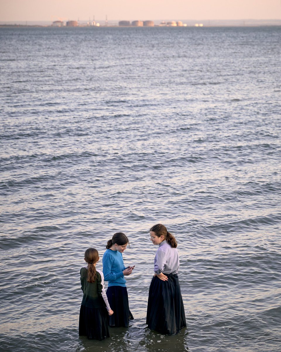 Three girls standing in the Thames Estuary. Southend-on-Sea.