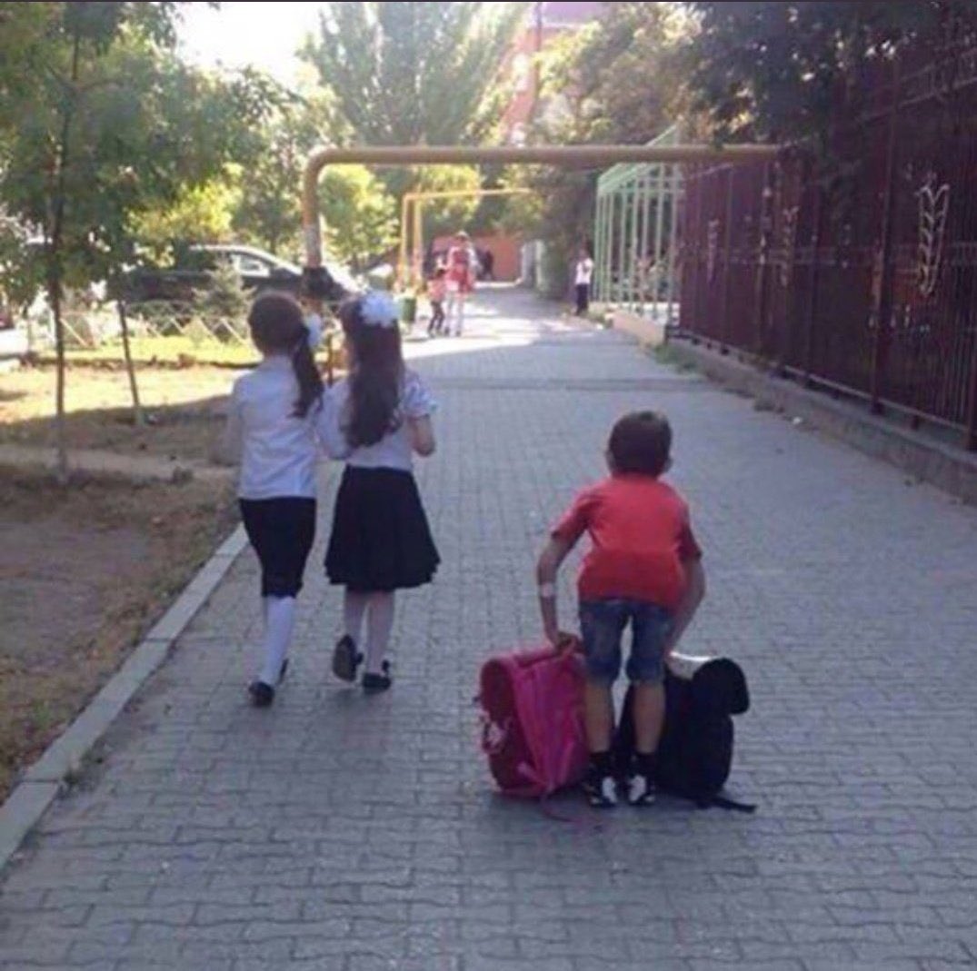 Мальчик несёт портфель девочке