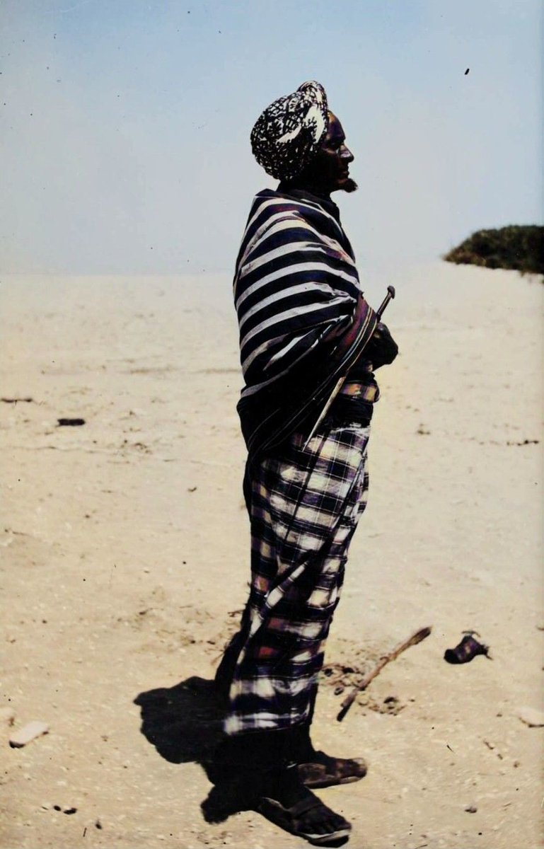 Portrait of a Habr Gidir Elder [1926]

Draped in an alindi printed huwasho (upper body wrap) and sarong (macawiis), wearing a turban (cimaamad) and leather shoe/sandal (kabo/jambal), with his hand rested on his long dagger (billaawe).