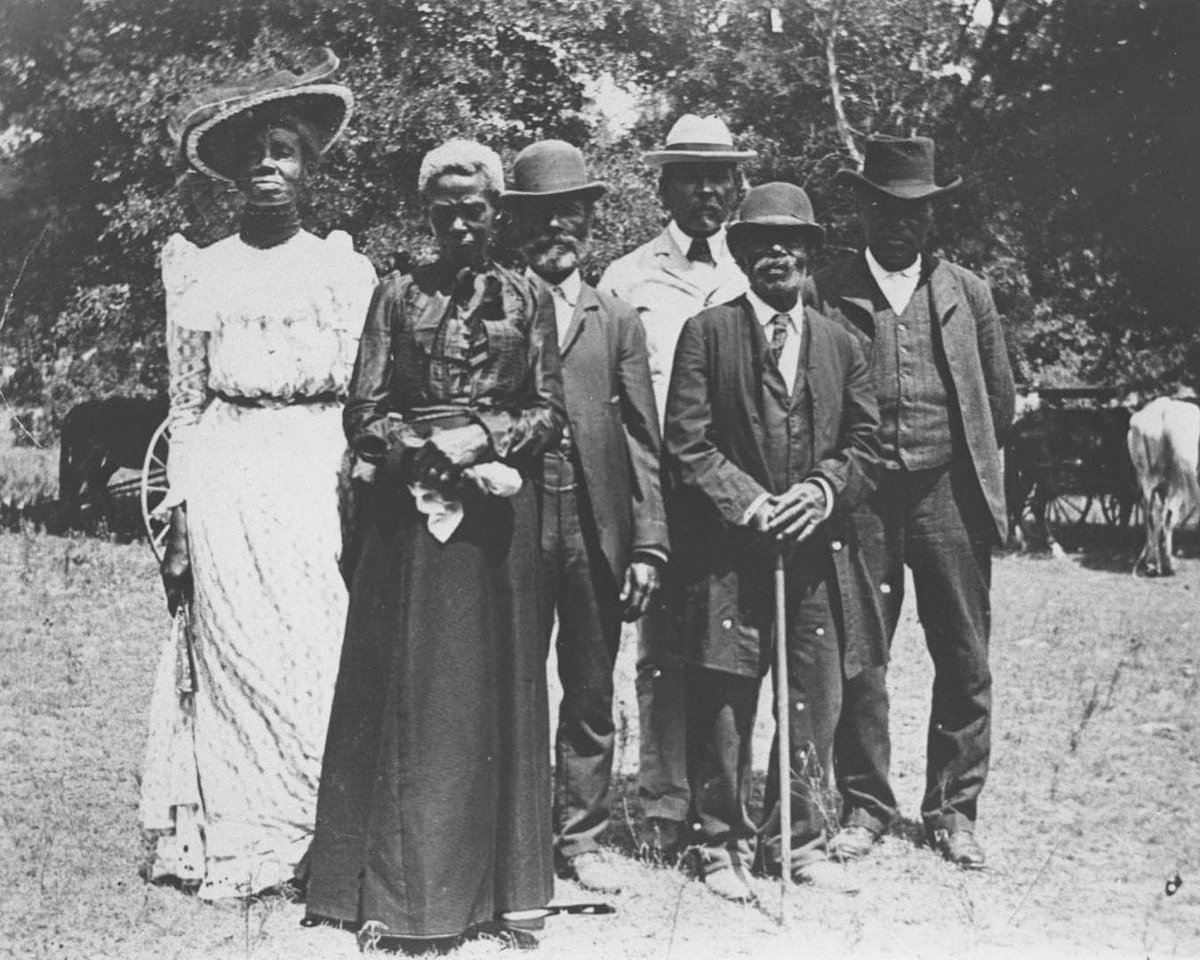 This is a photograph of an Emancipation Day celebration on June 19, 1900 in Eastwoods Park in Austin, Texas. A group of six well-dressed formerly enslaved individuals stand proudly before the photographer Grace Murray Stephenson, a young, white woman who lived nearby. Her