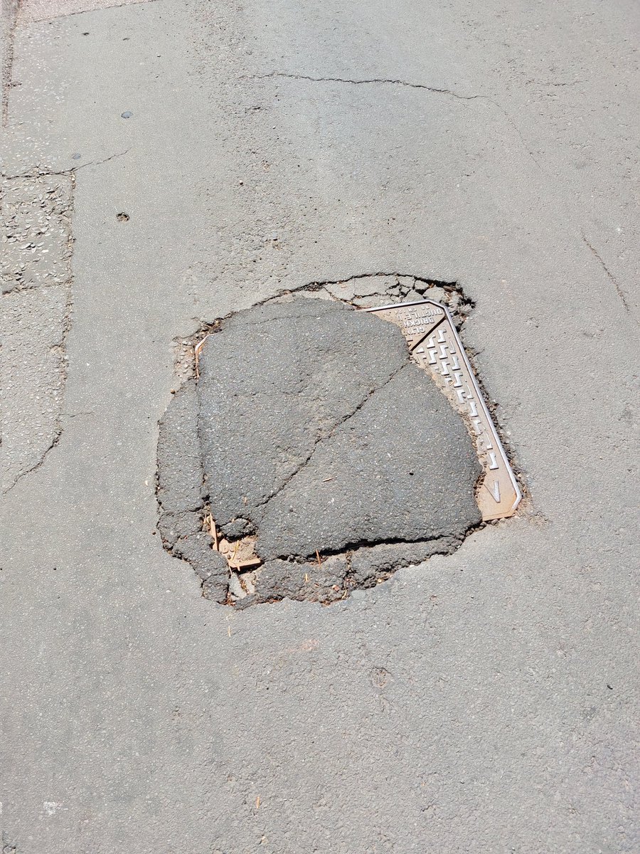 Classic Surrey County Council pothole repair. 
Subsided manhole cover. Repair perimeter reinforce  and raise drain hole. Subcontractor ..Nah .. chuck a shovel of tarmac on top of it. Pat it down . £500 job done..