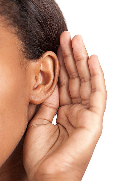 a Black woman holding her ear with one hand, her hair is partially straightened but her roots and edges are not straight...yet