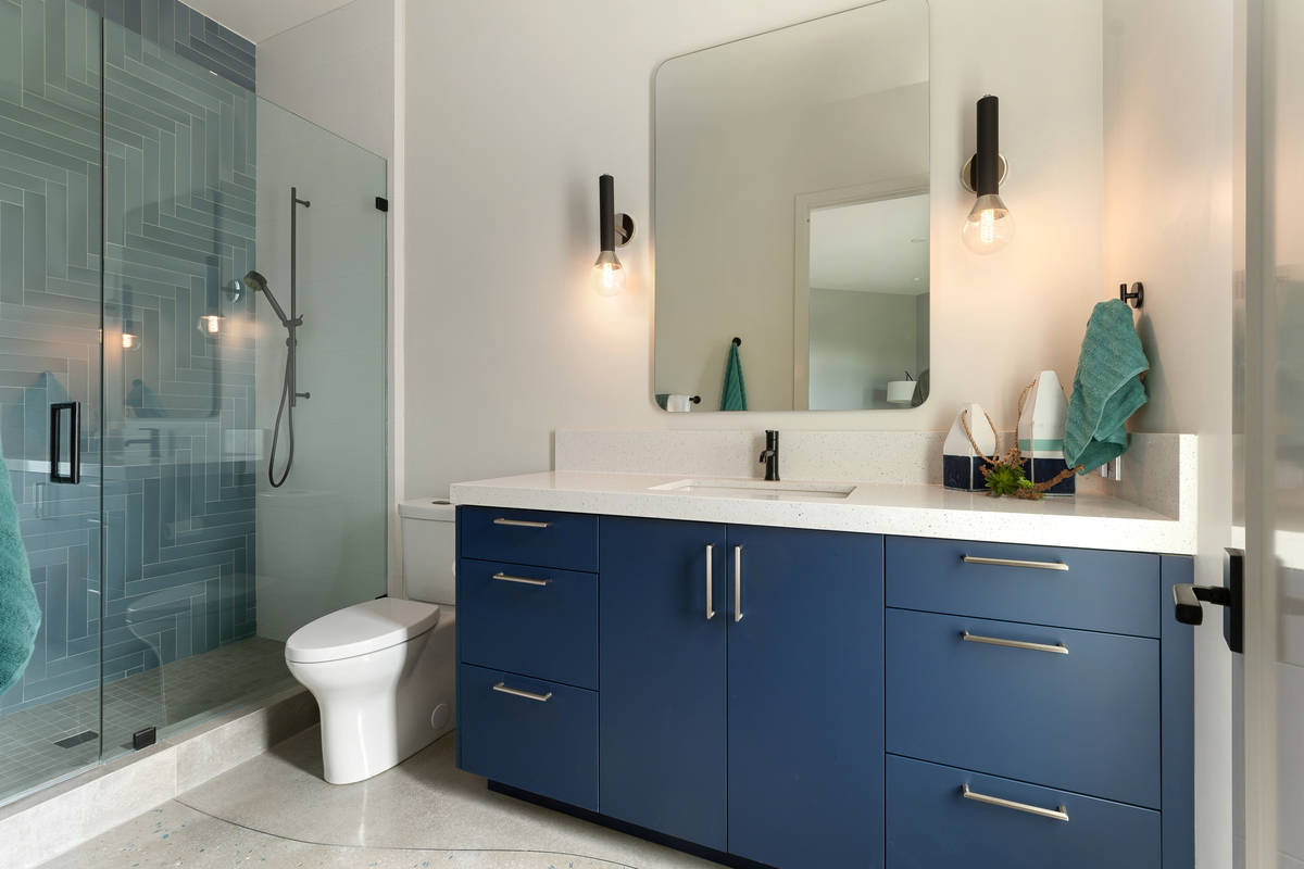 Blue cabinetry and dramatic tile design in the shower pop in this modern bathroom.