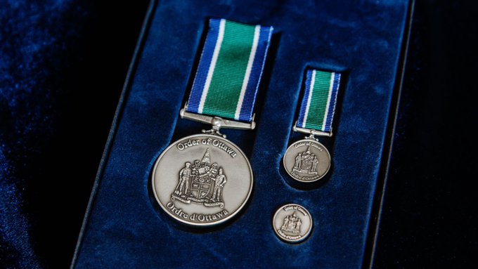 Un médaillon, une médaille et une pièce représentant l’emblème de l’Ordre d’Ottawa, reposant sur du velours bleu dans un coffret.