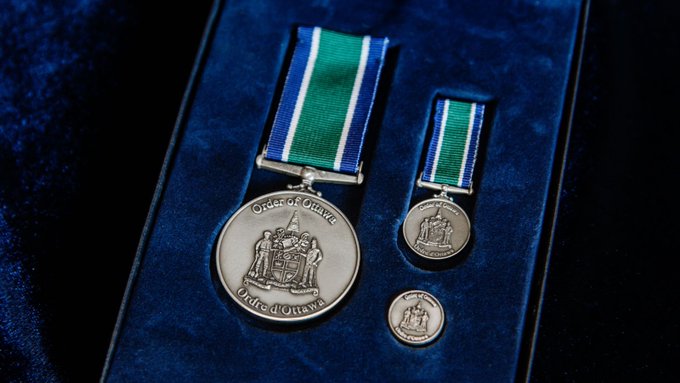 Un médaillon, une médaille et une pièce représentant l’emblème de l’Ordre d’Ottawa, reposant sur du velours bleu dans un coffret.