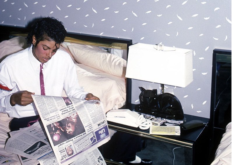 Michael Jackson reading a newspaper 
article about Prince’s “Purple Rain” (1984)