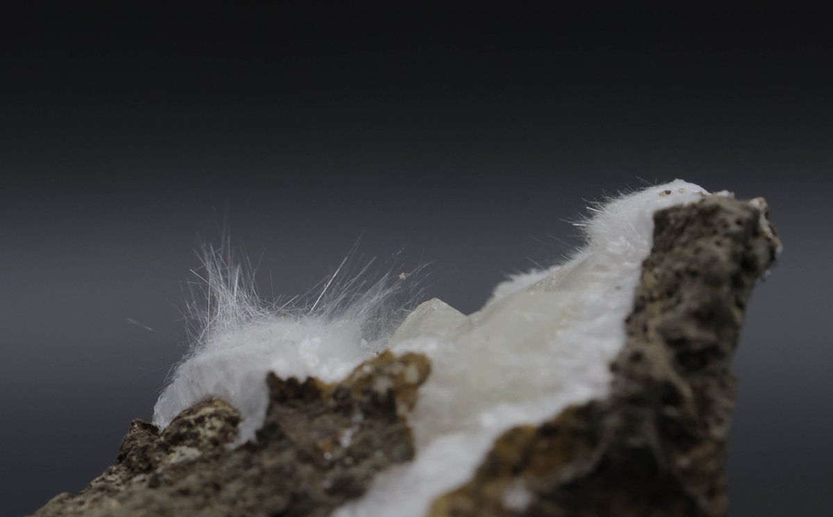 Found in altered volcanic rocks, natrolite crystals grow in slender prismatic needles. This type of crystal growth is known as “acicular,” which is from the Latin for “little needle.” With a fragile, pearly luster, natrolite adds a touch of elegance to the mineral world.