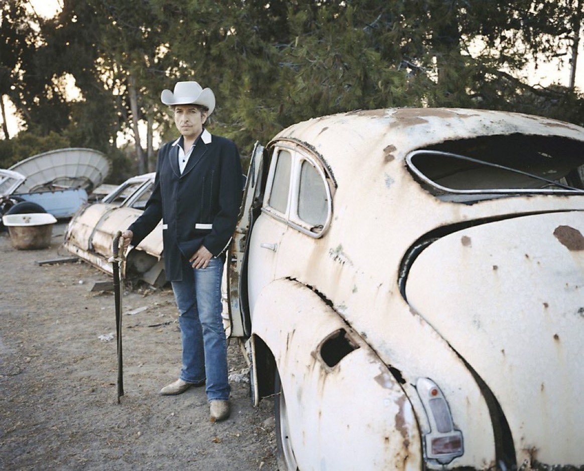 Bob Dylan stands next to an old abandoned car at home in Malibu, California, 2004. 📸: Brigitte Lacombe. #BobDylan #Dylan