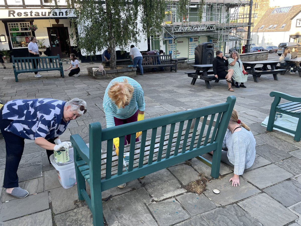 C_Dearden's tweet image. People power in action; volunteers repaint the benches in Conwy’s Lancaster Square