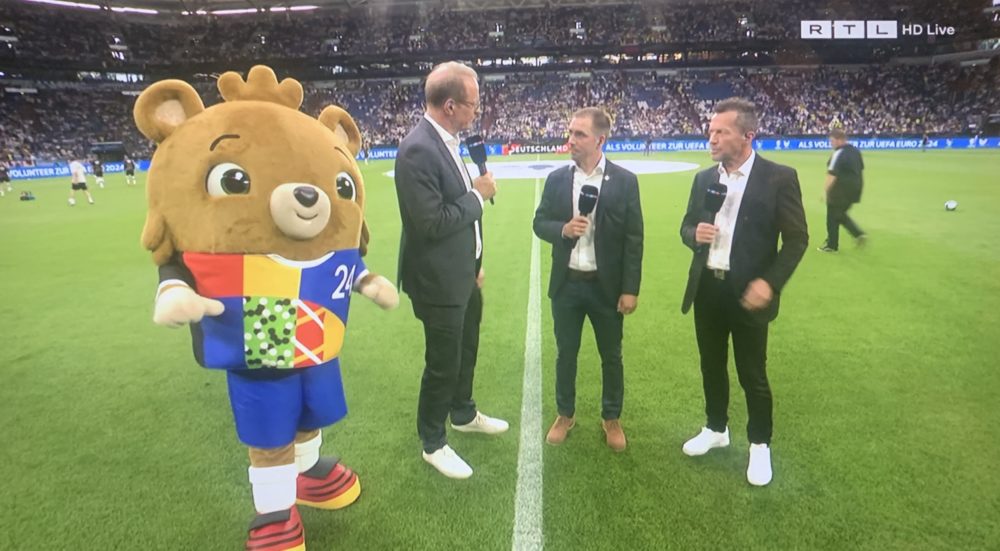11Freunde_de's tweet photo. Och nee, wie süß! Wir starten direkt mal mit einer guten Nachricht: Zum ersten Mal ist das kleine schnuckelige Maskottchen der EM 2024 zu sehen. Und direkt neben Philipp Lahm steht so ein komisches Plüschtier mit Hose. Naja. #GERCOL https://t.co/3ug3m90Ts8