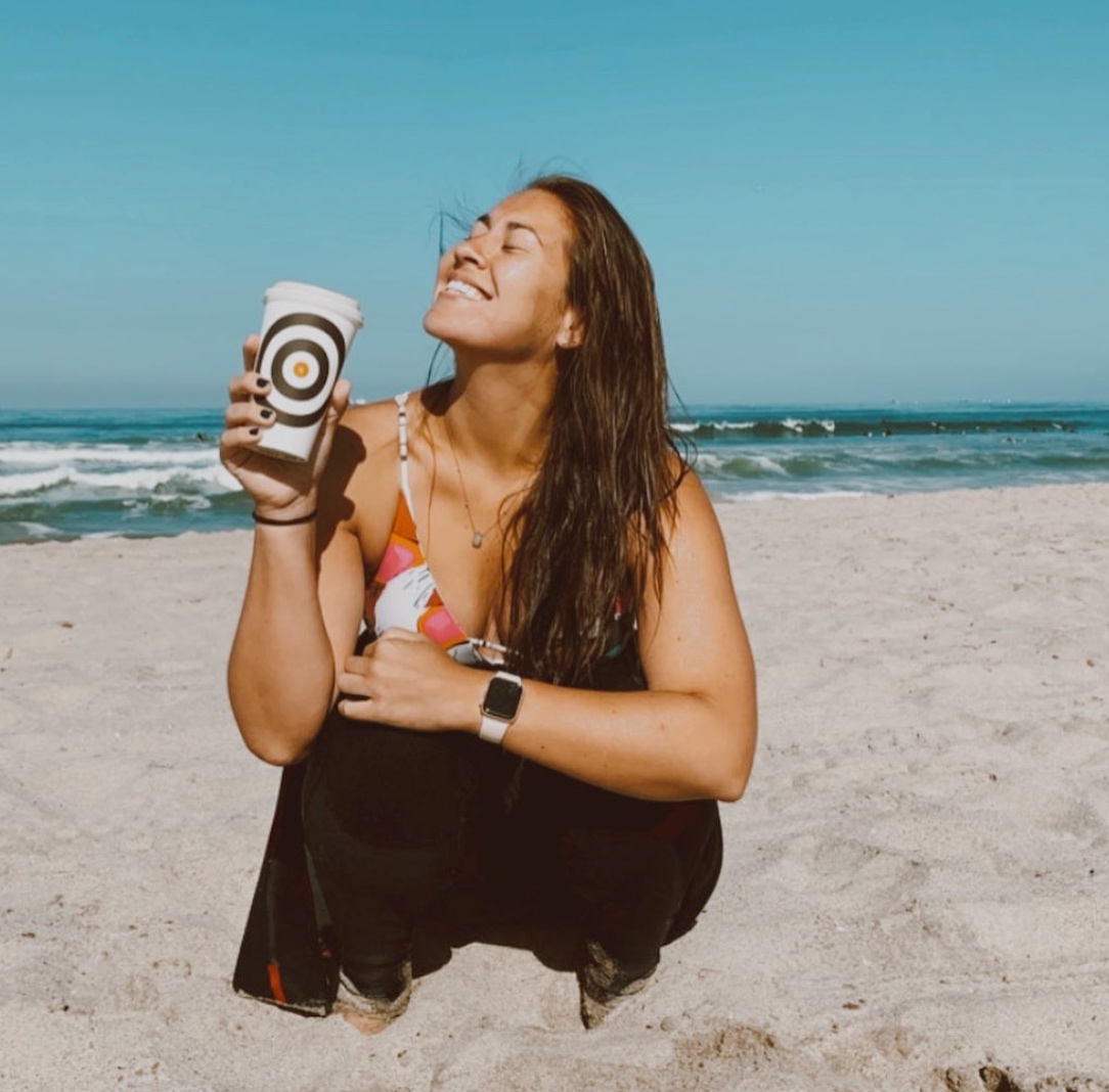 Nothing says 'summer is here' like a Two Guns latte and a killer morning session. Bliss out with us before you paddle out. 

📸: @eliseee_T 

#ImageDescription: A surfer smiles and holds her Two Guns drink high as she crouches in the sand to sip and pose before heading into th...