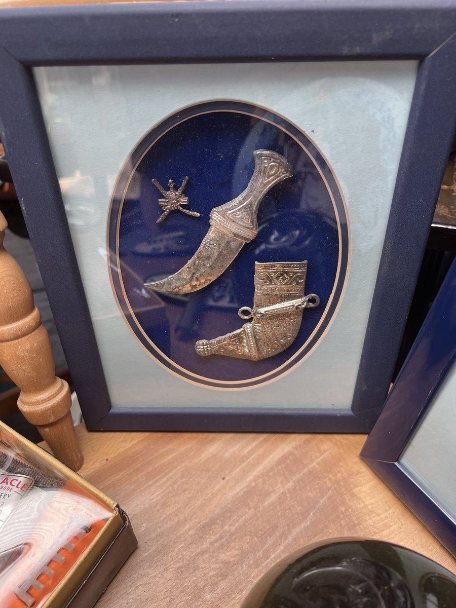Basha1972's tweet photo. Spotted this in a Antiques shop today, Omani  Khanjar ornament in picture frame, bit coincidental it’s the SAS Regimental Colours, albeit a bit faded 🧐 #souvenir #mirbat #Dhofar #Oman  #SAS https://t.co/fbDLY2UUy5