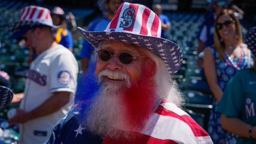 A fan with a beard dyed with red, white and blue stripes, wears today's giveaway item – an American flag patterned 