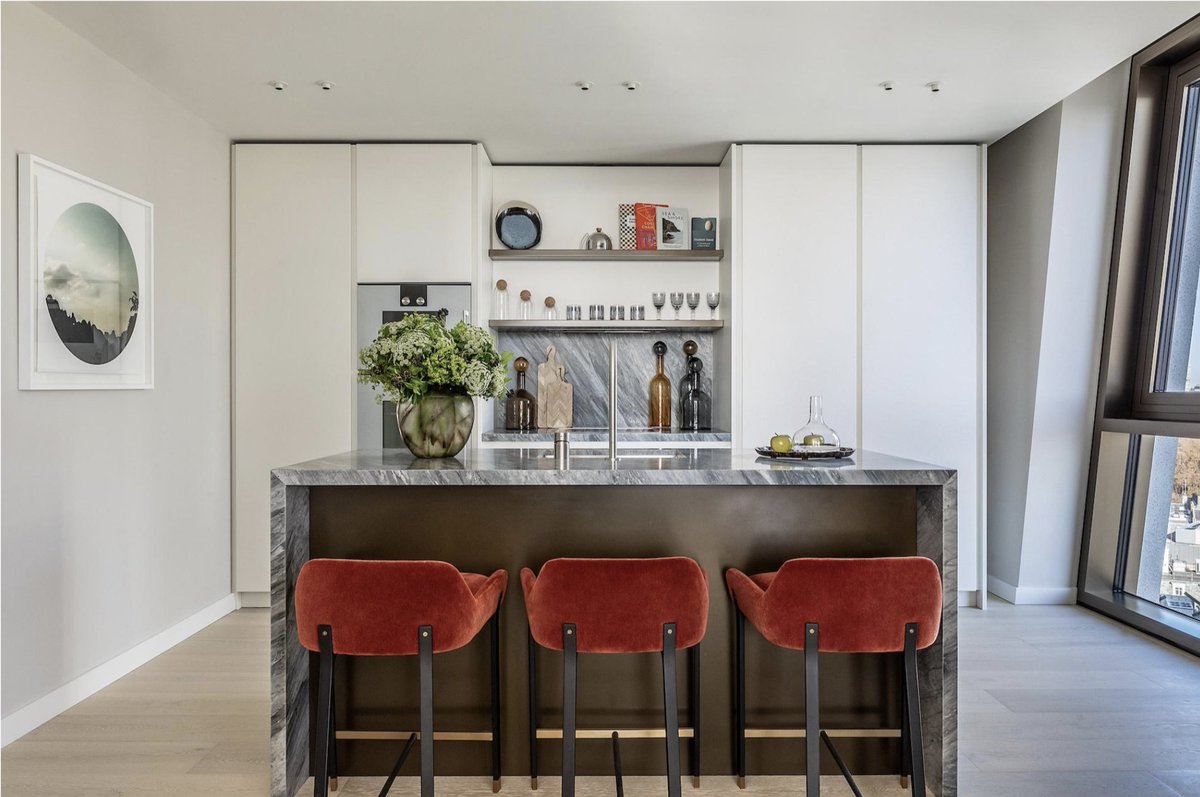 Unexpected colours and fabrics transform a kitchen from utilitarian space to a cosy room for living. Here we used russet velvet stools, vibrant photography and sophisticated accessories.  I love placing an oversized floral arrangement on the counter for dramatic impact.
