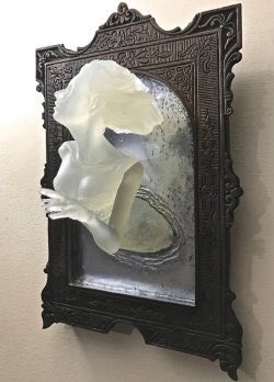 Sculpture of a Victorian ghost emerging from an antique mirror cast in resin.