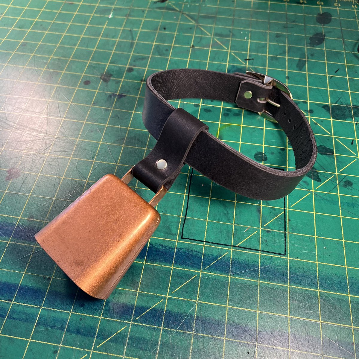A custom cowbell collar for @scumbelievable made from a black latigo leather strap and lined with the kind of hide you're supposed to use for motorcycle jackets