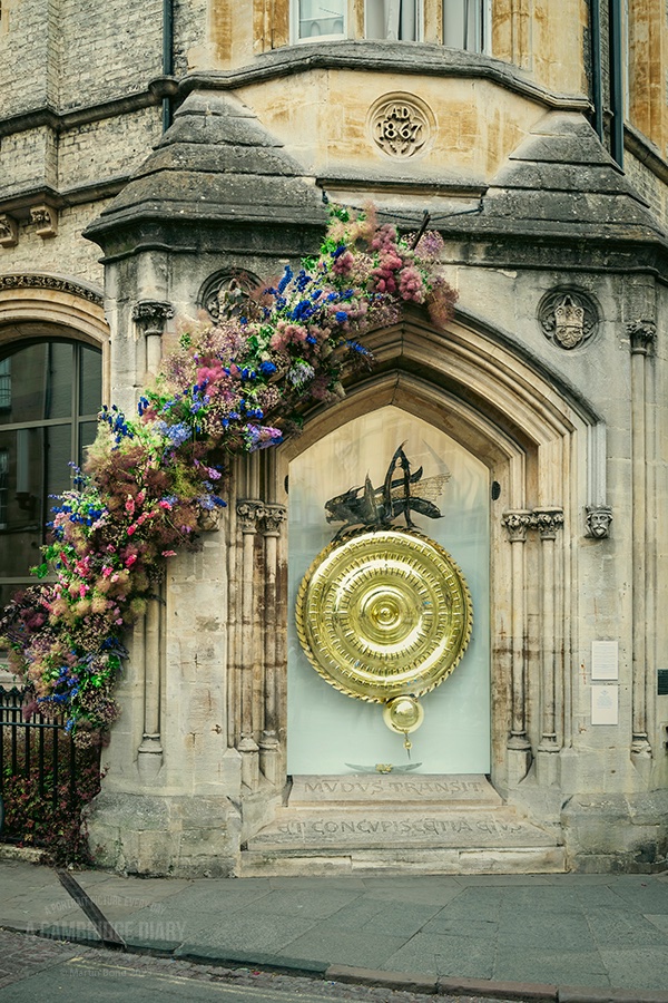 Love it or hate it (and opinion is firmly divided), the Corpus Clock is once again visible after months of being boarded up whilst being repaired after the protective glass was vandalised.

To mark the occasion and to celebrate British Flower Week, The Cambridge Hub of Flowers