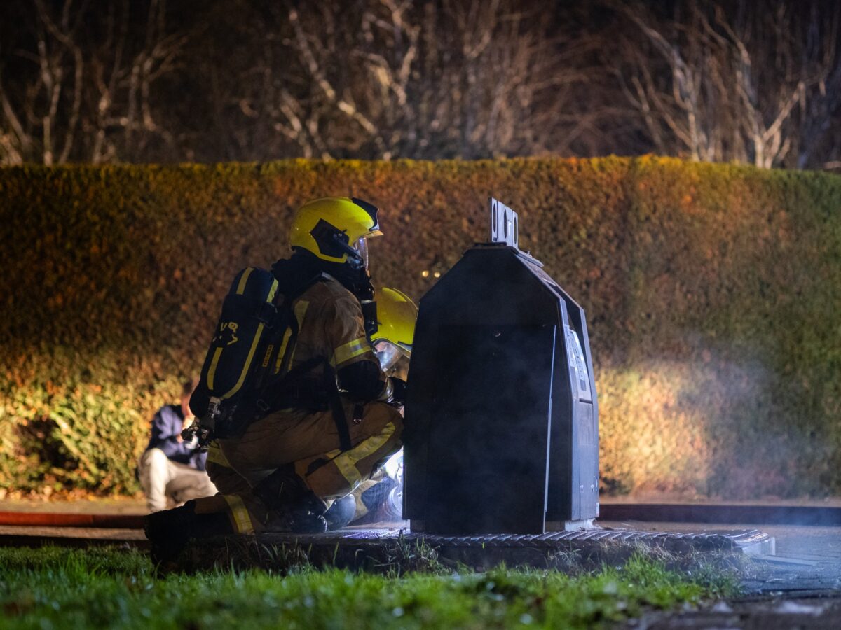 Brandweer blust vuur in ondergrondse afvalcontainer