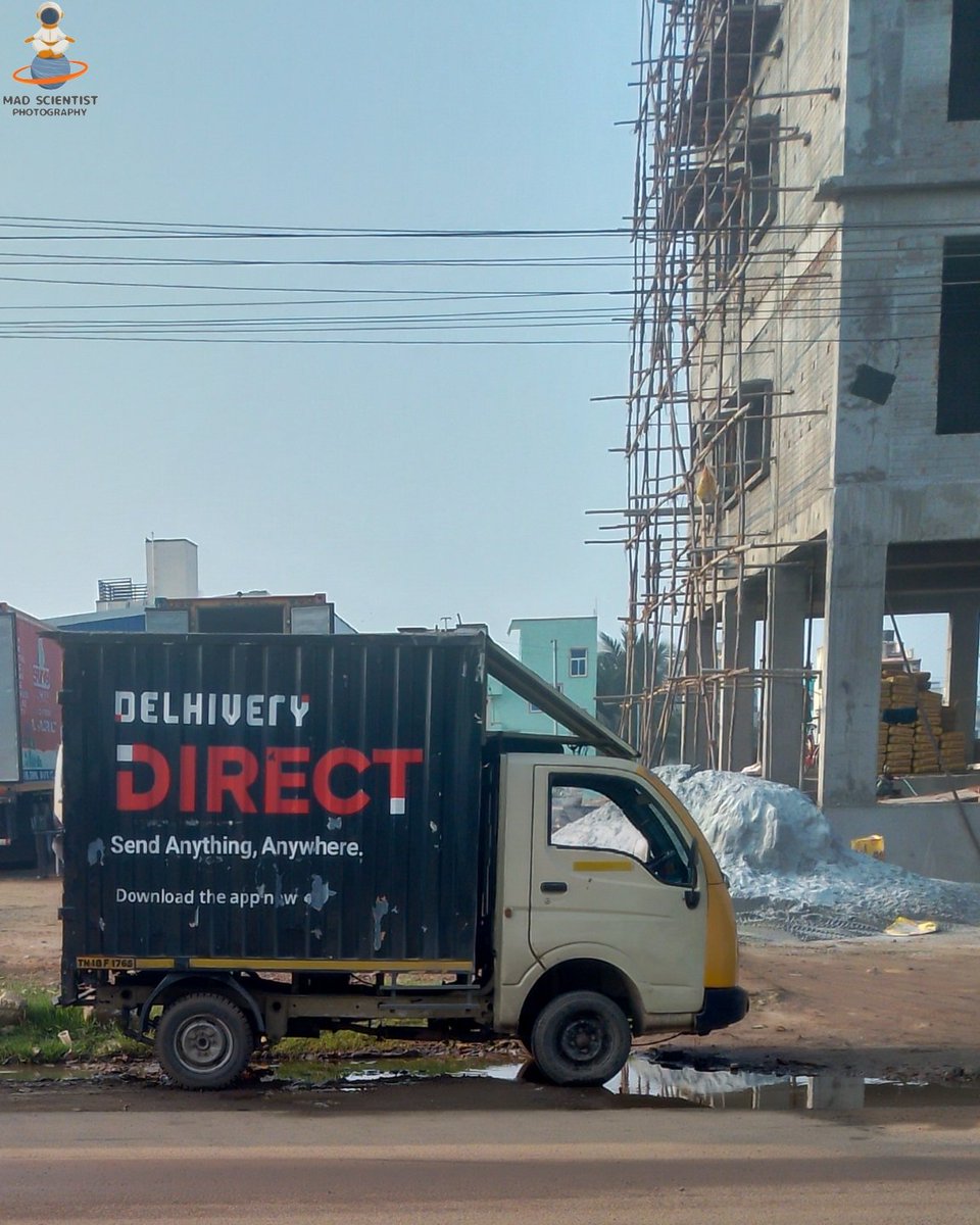 mad00scientist's tweet photo. Captured this shot of a Delhivery truck framed by the raw textures of urban growth. The contrast between the rigid scaffolding and the bold branding caught my eye. 🚚🏙️
​"Send Anything, Anywhere"—even through the dust and grit of progress.
​#Photography #madscientistphotography https://t.co/pa6pVyIyjG