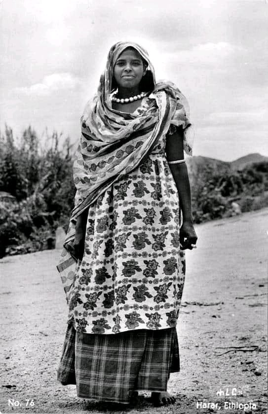 BaatiPartyArt's tweet image. Somali woman, Harar 1953 

She is wearing a flower-print kurdad (dress) and plaid gorgorad (petticoat), a very common style. 

She is also wearing the typical fishnet gambo (headwrap) and silver murriyad (bead necklace) typical of wedded Somali woman.