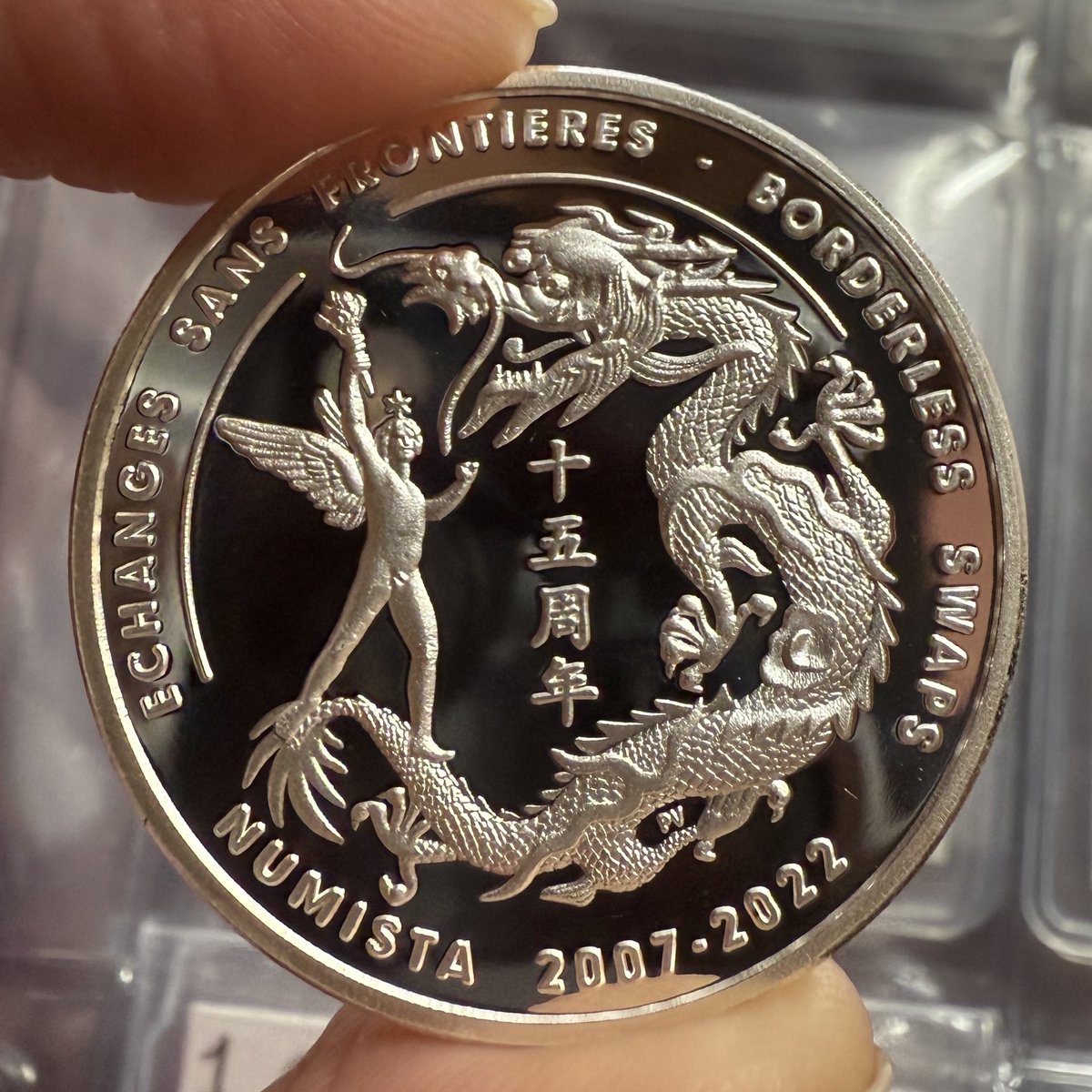 The other side of the silver medal. Its design is inspired by French and  Imperial Chinese coins.