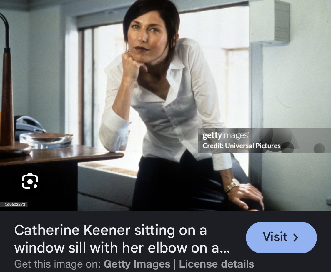 Catherine Kenner sitting on a window sill with her elbow on a table