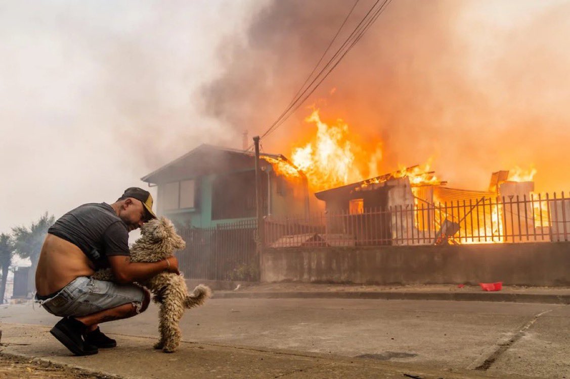 Chile 🇨🇱 : Un hombre acaricia a su perro después de que su casa se incendiara durante los incendios forestales en Lirquén, justo al norte de la ciudad de Concepción.  
Imagen de Javier Torres/AP.