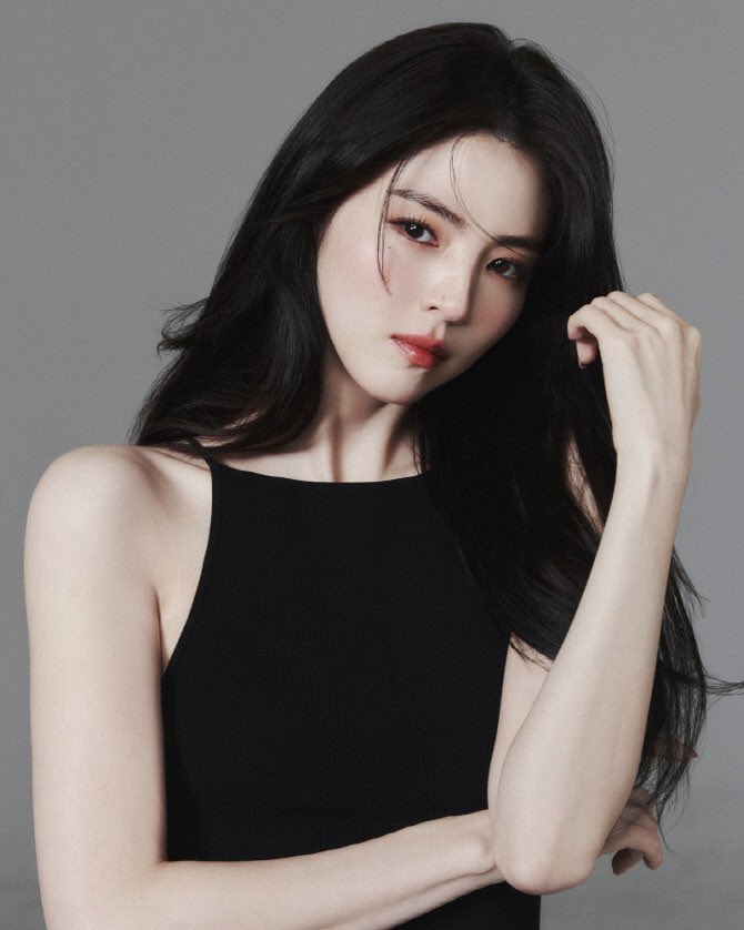 She stands in stillness, moonlit and composed, a quiet storm behind her eyes, elegance unfolding like wings learning how to remember flight at dawn softly.