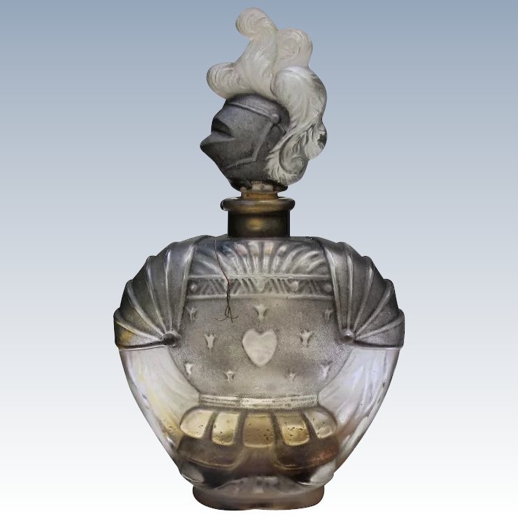 Chevalier de la Nuit’ perfume bottle designed by Julien Viard, c. 1923–1924; moulded clear-and-frosted glass with patinated relief, the stopper formed as a plumed knight’s helmet.
