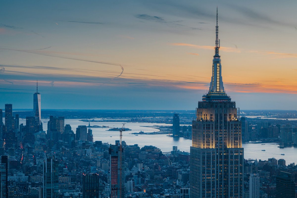 Writing_Niche's tweet photo. Look at this majestic image of the skyline, taken during the twilight hour of NYC. 

Beautiful illumination of the top floor windows for the Empire State building too. 

The sound of music is making its way to the skyline, ascending beyond the open clouds, shortly before piercing the spectrum of colours offered by the sky.