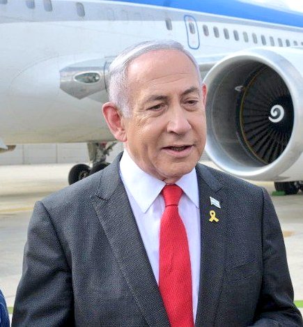 Benjamin Netanyahu wearing a dark suit, white shirt, red tie, and a yellow ribbon pin, standing in front of a large airplane with a blue and white exterior. Ursula von der Leyen wearing a yellow jacket and white shirt, standing against a blue background with yellow stars.