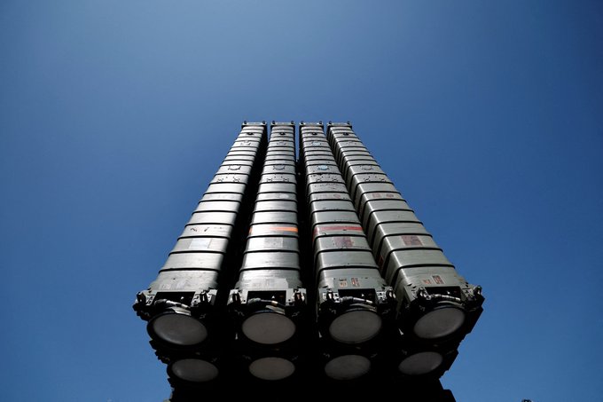 Multiple vertical missile launchers arranged in four rows, each containing several cylindrical missile containers. The containers are gray with some orange markings. The launchers are positioned against a clear blue sky.
