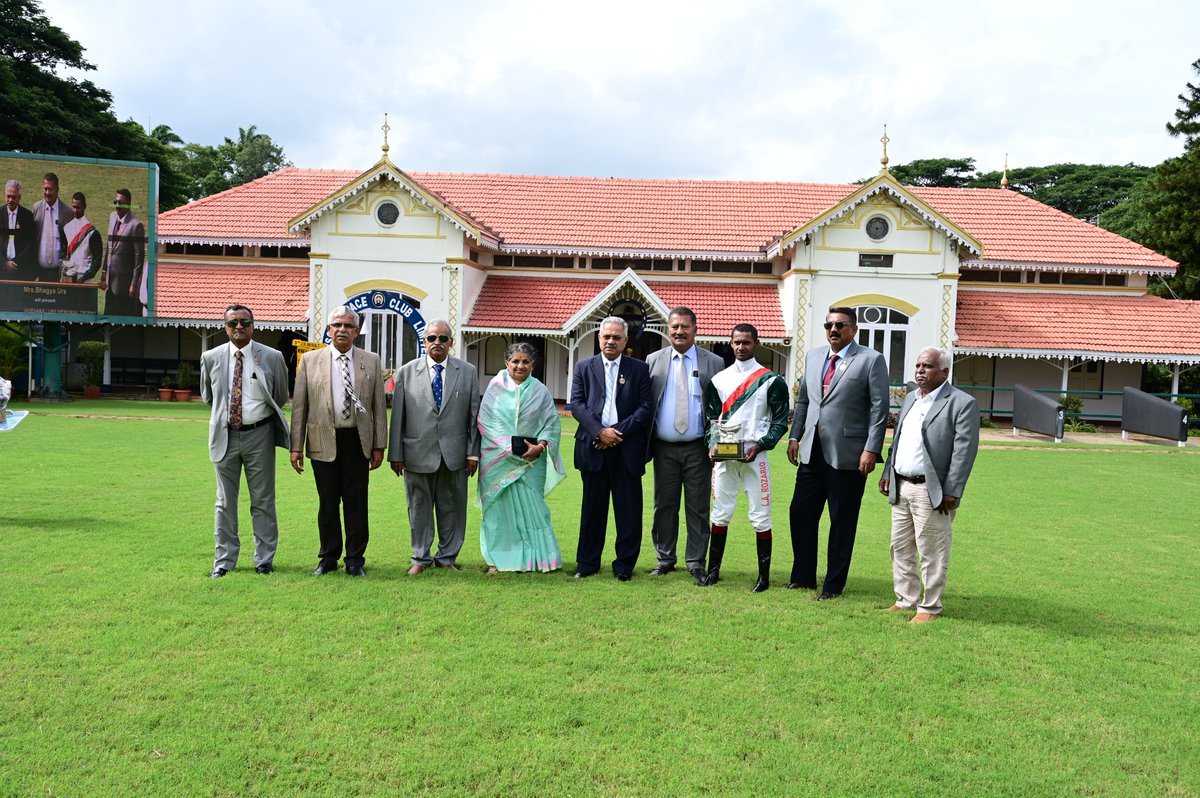 Mrs. Bhagya Urs,Presenting,
“The B K Krishnadevaraj Urs Memorial Trophy”
To the Winner – AGERA
Jockey –  L Alex Rozario
Trainer –  K Pradeep Annaiah
Trophy received by – K Pradeep Annaiah
Owner – Mr V Shankar
Others in the photo: Chairman and Stewards/Committee Members of MyRC.