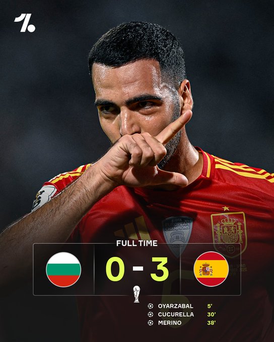 A man wearing a red Spain national soccer jersey with a star and emblem on the chest, making a hand gesture near his face. A scoreboard overlay shows Bulgaria 0-3 Spain, with goal scorers Oyarzabal, Cucurella, and Merino listed, along with the text "FULL TIME" and World Cup qualifier details. A watermark with "1." is visible in the top left corner.