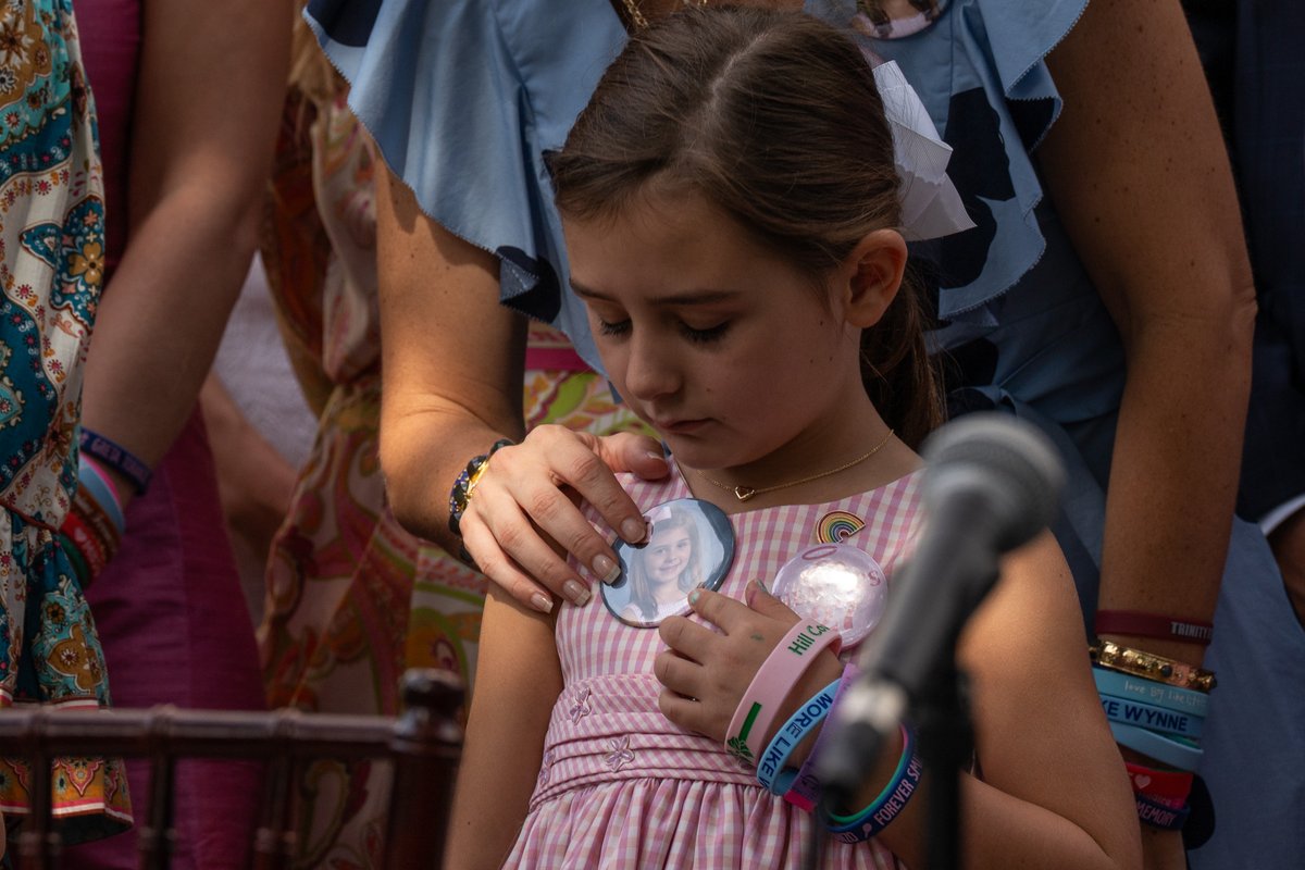 Emmalynn Lytal touches a button honoring her sister, Kellyanne Lytal, who lost her life in the July 4th flooding at Camp Mystic. <a href="/GregAbbott_TX/">Greg Abbott</a> signed into law a bill that bans the state from licensing youth camps with cabins in a floodplain, vowing the response will save lives.