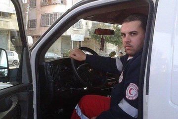 A child wearing a black graduation gown and cap, holding the cap with one hand, standing indoors near a table with tulips in a vase. An ambulance with Arabic text and the word "AMBULANCE" on it, a person in a red uniform standing beside it. A person in a uniform driving the ambulance, visible through the driver’s window. Rows of bullet-shaped icons arranged in a grid pattern.