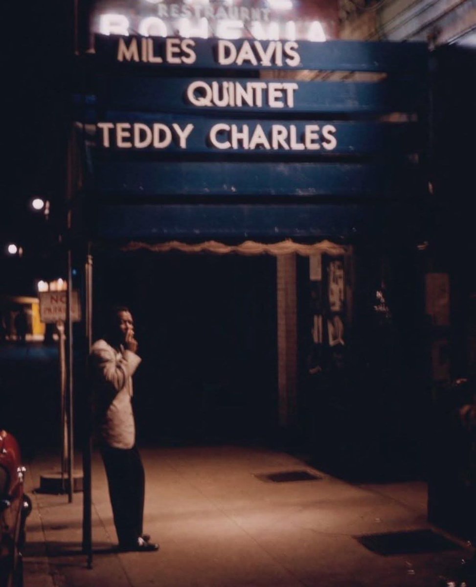 Miles Davis smoking a cigarette under the marquee of the jazz club Cafe Bohemia in New York City (1956)