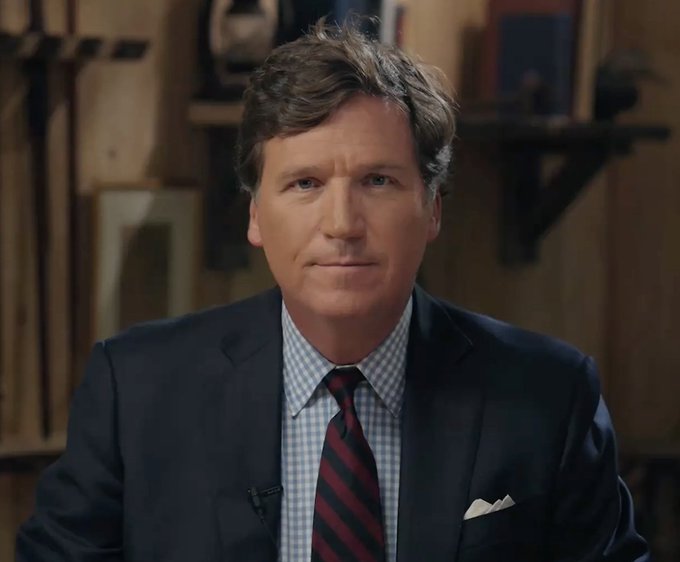 Tucker Carlson wearing a dark suit, white shirt, red and black striped tie, and pocket square, standing in a room with shelves and objects in the background. Vladimir Putin wearing a dark suit, white shirt, black tie, and a yellow and black ribbon pin, standing among individuals in military uniforms with medals.
