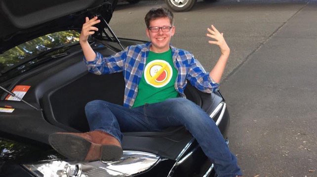 Erik Finman sitting in a car trunk smiling