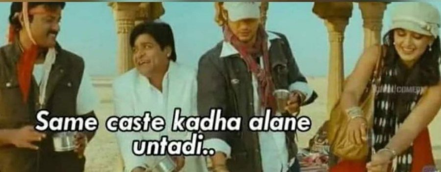 Four people standing outdoors near stone pillars, dressed in casual and colorful outfits. One person wears a white cap, another a red jacket, and a third a black jacket with a scarf. A woman in a black and white dress holds a bag. Text overlay reads "Same caste kadha alane untaadi..".