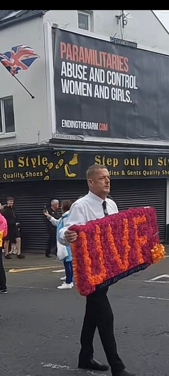 This photo should be used in all the local newspapers throwout NI 
READ THE BILLBOARD about the the guy who's carrying a homegrown British terrorist floral display of the UVF