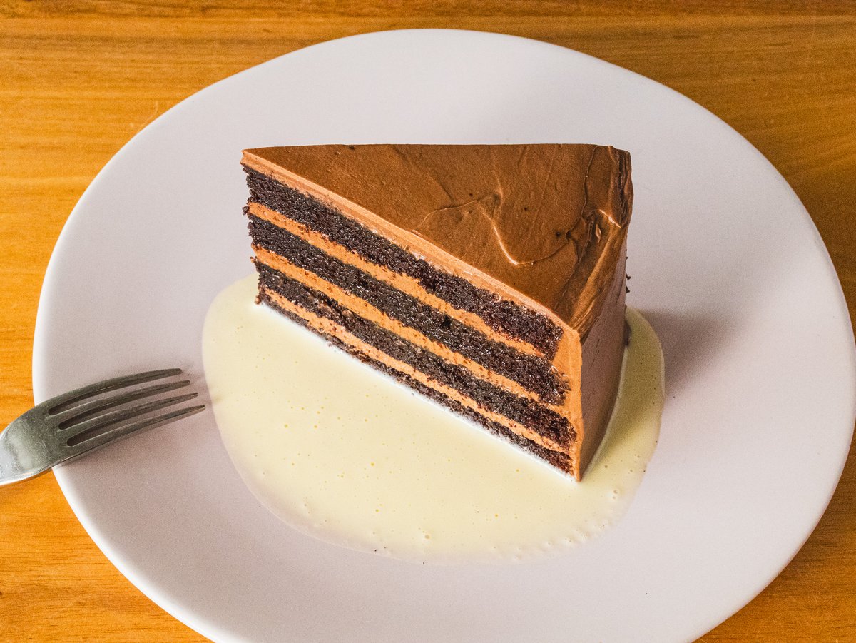 Not just dessert—a flex. Steffie Kay’s Chocolate Cake: fudge, mocha buttercream, vanilla anglaise. One slice, zero regrets. 🍰🔥