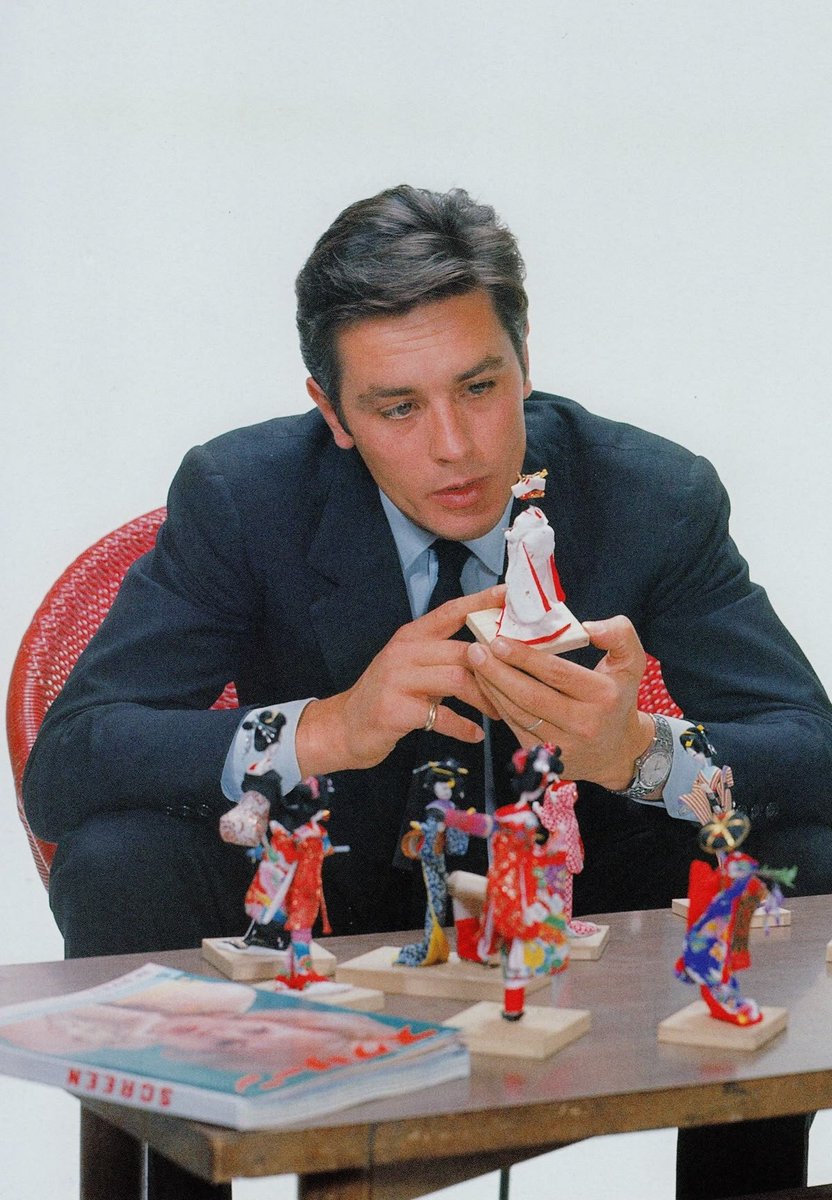 Alain Delon with Japanese dolls during a visit to Japan, circa 1963.