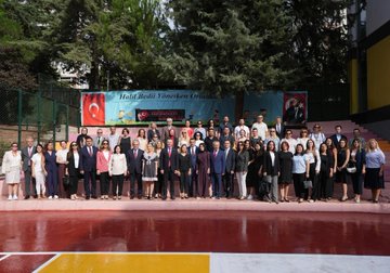 A group of people, including students in black uniforms and adults in formal attire, standing in rows on a yellow and green marked pavement outside a building with a sign reading "Halil Bedii Yönetken Ortaokulu." A man in a blue suit shakes hands with a student. Inside, people sit around a long table in a meeting room with bookshelves and a screen displaying a logo. Another image shows a large group of people, including students and adults, posing together on a red surface with banners in the background.