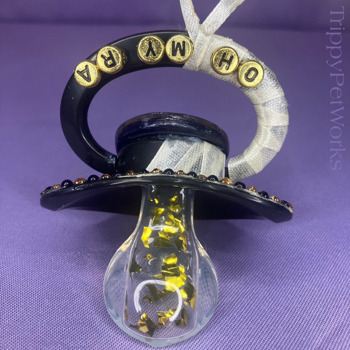 TrippyPetWorks's tweet photo. Cleo’s pacifier features a Completely Handmade resin centerpiece and dangle charm! A unique black and gold Rhinestone/ faux pearl design with character personality in mind! Bandages (ribbon) And the nipple filled with gold flakes! Always durable for worry-Free Use!˚𝜗𝜚˚⋆ https://t.co/hRvlWirSjH
