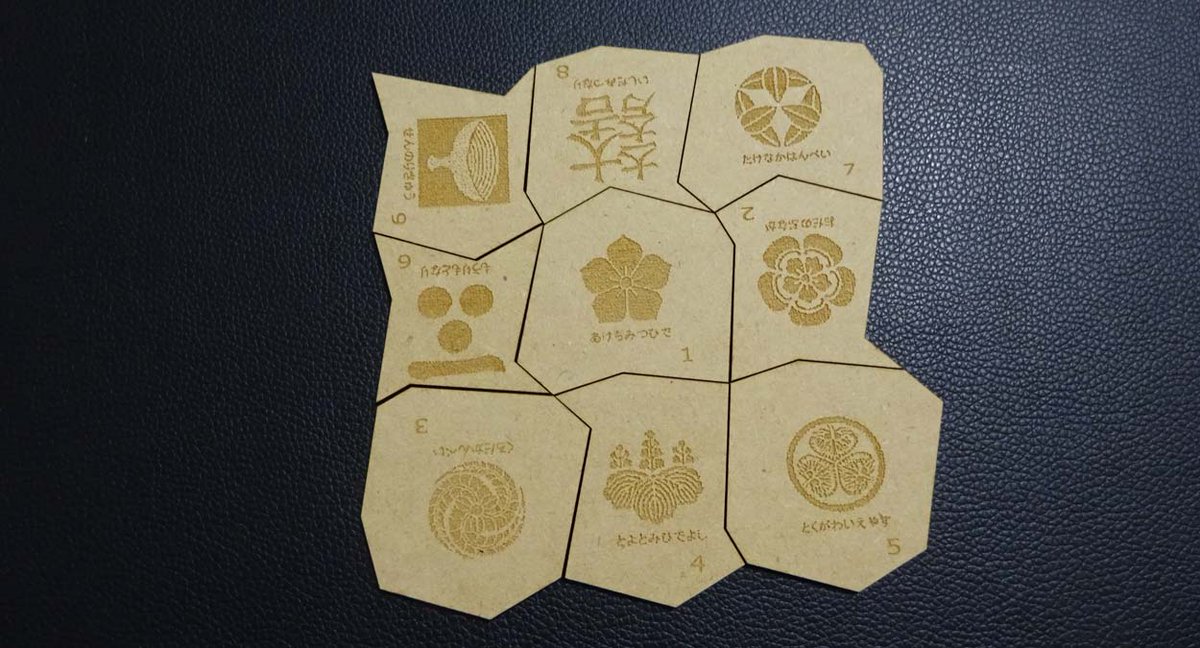 色々な形にカットされた９個のピースを組み合わせて3×3の形を作るパズル。どのピースを真ん中に置いても答えが１つずつある。当時佐伯氏は家紋に関心を持っていて素材とした。答えを出そうと並べてみるが9通りの答えを出すまでにはかなりの時間がかかりそうだ。