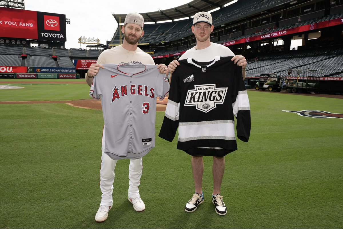 Los Angeles Angels outfielder Taylor Ward and Los Angeles Kings player Taylor Ward hold up their respective jerseys as they pose for a photo together on the field at Angel Stadium.