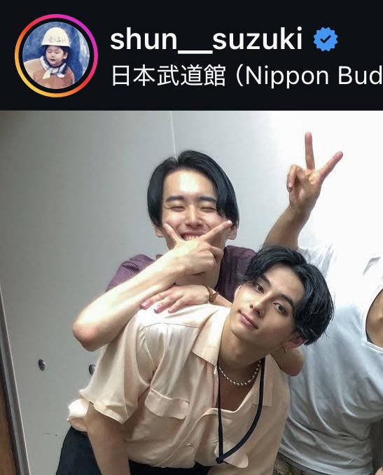 Shun Suzuki posing with two individuals, one making a peace sign, wearing casual shirts and jackets. Three individuals in matching red, white, and black jackets making peace signs in front of a screen displaying Japanese text and the Kaze logo. A large group of individuals in black outfits posing together on a green surface with a blue backdrop, some making heart gestures.